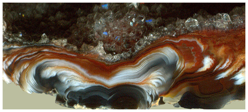 Агат | Деталь строения стенки жеоды чёрно-красного агата сфероидолитово-дендритного строения с кристаллами кварца на внутренней стенке. Ширина поля 2см. Бразилия